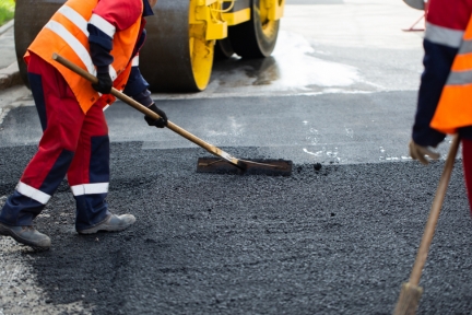 Powerhouse crew performing asphalt repair and resurfacing on a commercial parking lot.